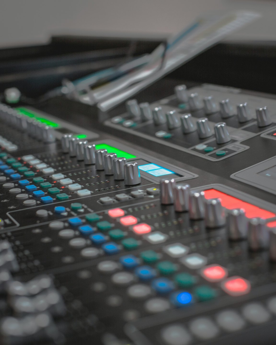 Professional audio mixing console with illuminated buttons and knobs.
