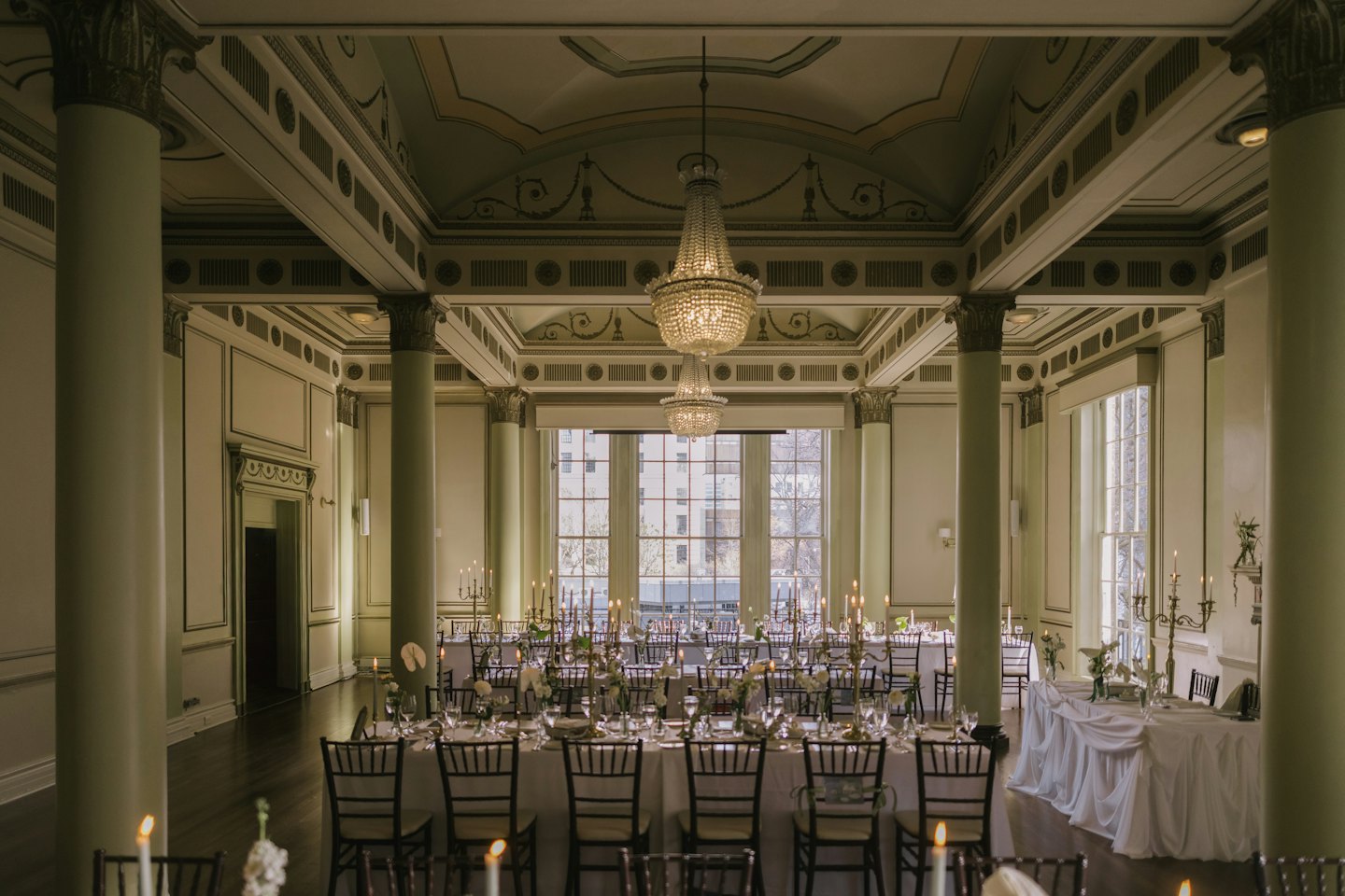 Elegant ballroom set with candlelit tables and floral arrangements.